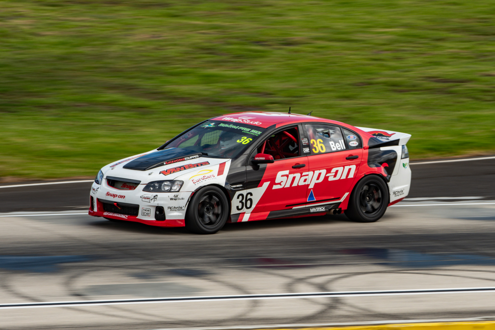 Red and white touring car at speed on a racing circuit