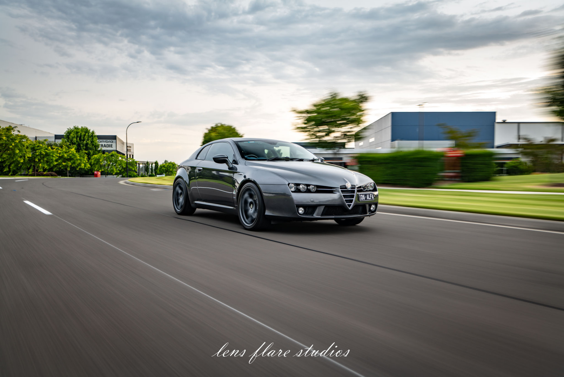 Grey sports car driving along a suburban road