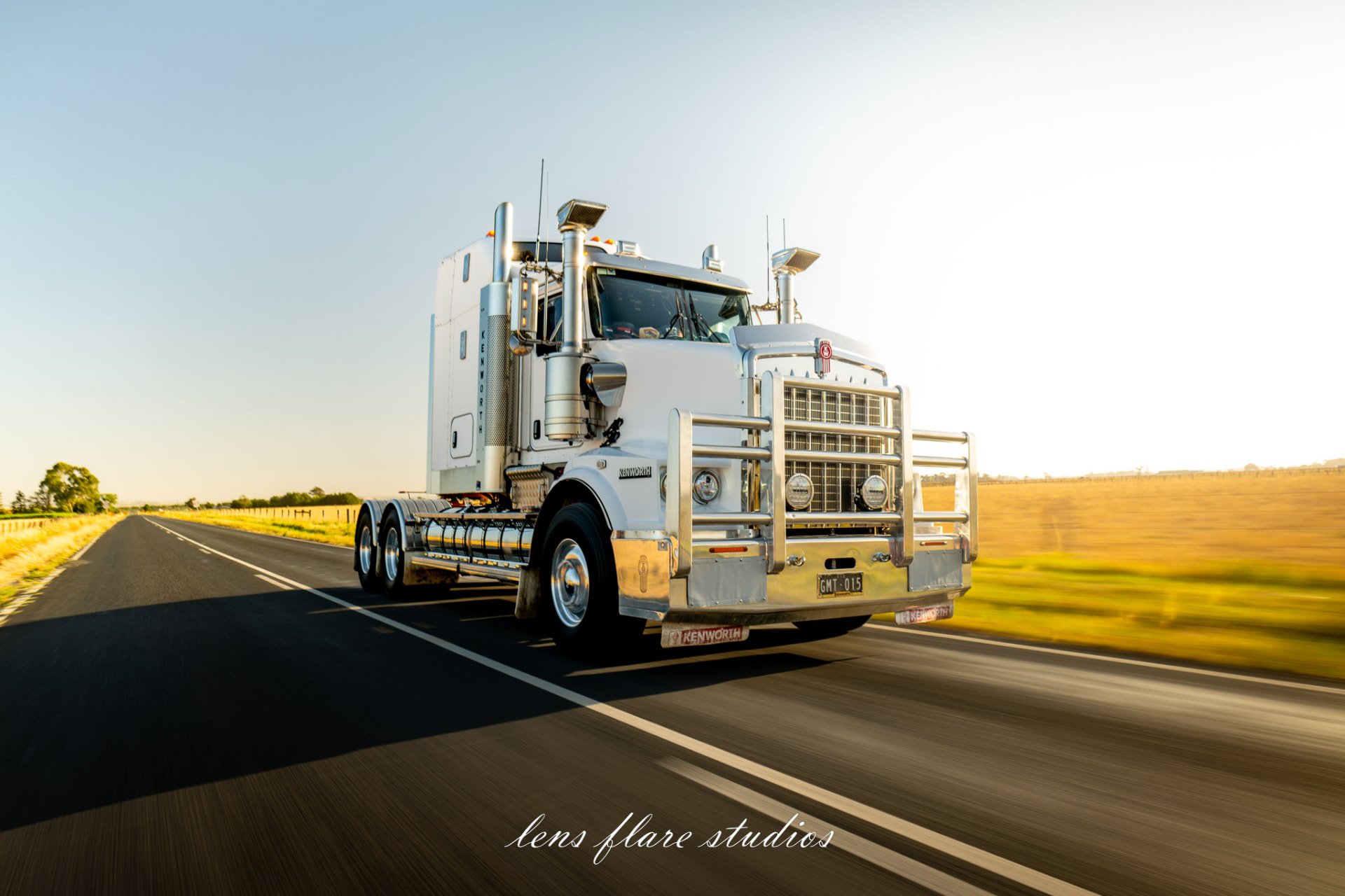 White truck travelling along a sunlit country road
