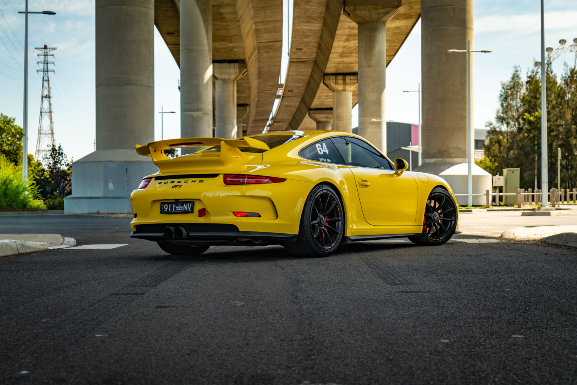 Yellow sports car beneath a concrete overpass